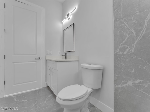 bathroom featuring marble finish floor, baseboards, vanity, and toilet