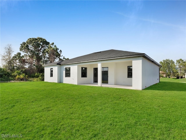 rear view of house featuring stucco siding, a lawn, and a patio