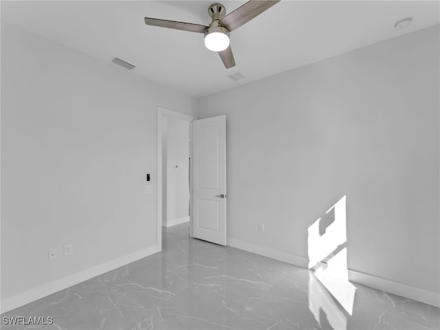 empty room with marble finish floor, baseboards, visible vents, and ceiling fan