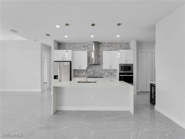 kitchen featuring stainless steel appliances, light countertops, white cabinetry, and wall chimney range hood