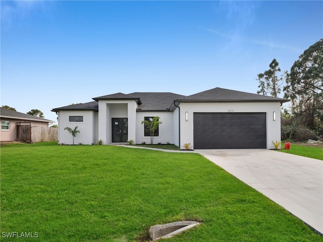 prairie-style house with stucco siding, fence, a garage, driveway, and a front lawn