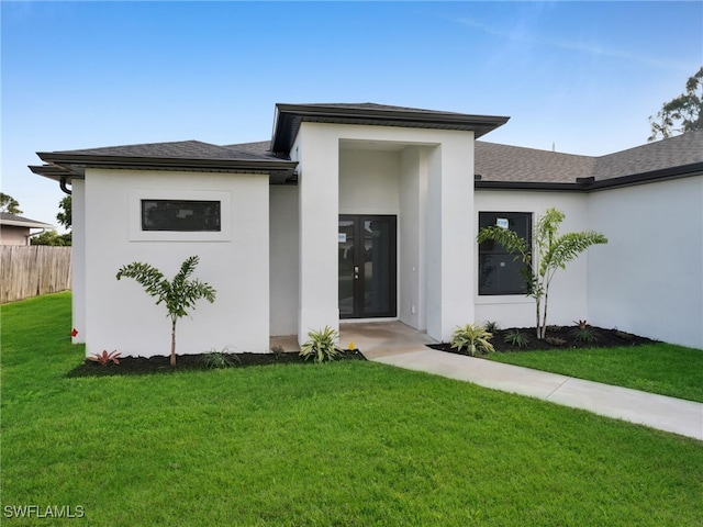 view of front of property featuring roof with shingles, fence, french doors, a front yard, and stucco siding