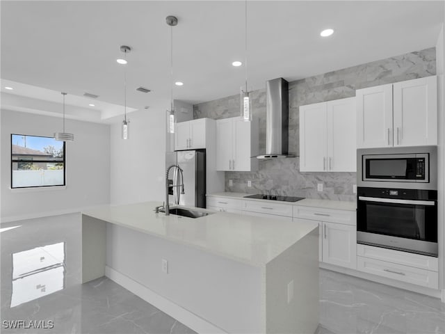 kitchen with appliances with stainless steel finishes, wall chimney range hood, decorative light fixtures, and white cabinets