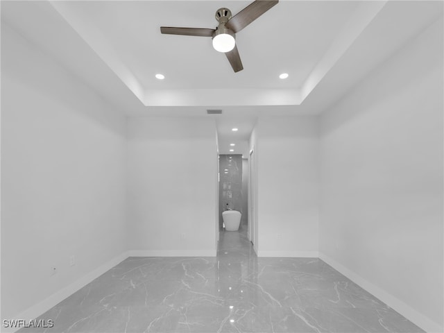 empty room featuring baseboards, visible vents, a raised ceiling, and recessed lighting