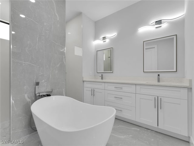 full bathroom with a freestanding bath, marble finish floor, double vanity, and a sink