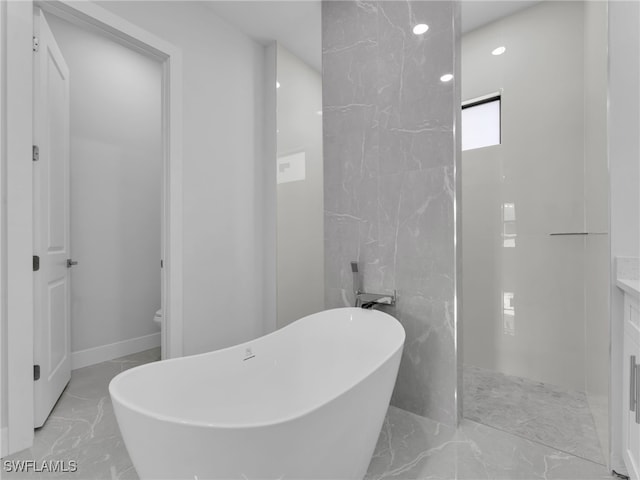 full bath with marble finish floor, a soaking tub, and vanity