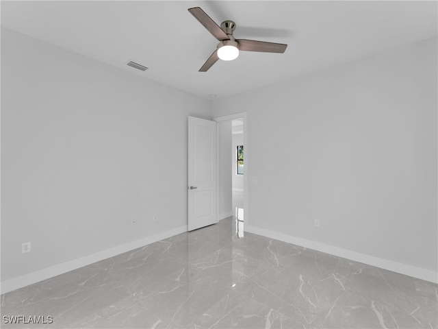 empty room with marble finish floor, visible vents, ceiling fan, and baseboards