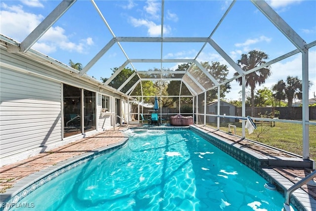 view of swimming pool featuring a lanai, a fenced backyard, a storage unit, and an outbuilding