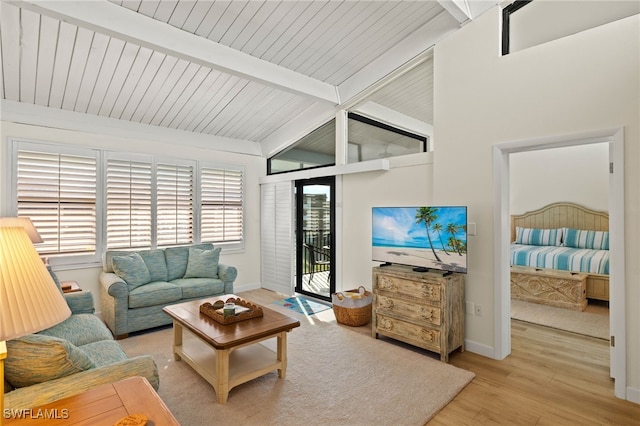 living area featuring baseboards, vaulted ceiling with beams, and light wood finished floors