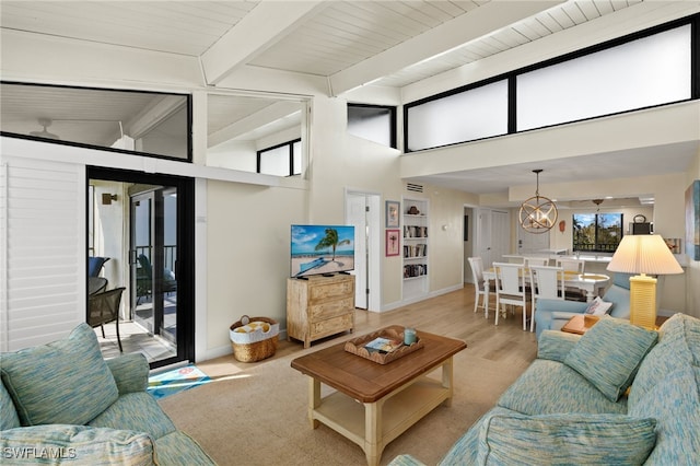 living area with vaulted ceiling with beams, light wood-style flooring, baseboards, and an inviting chandelier