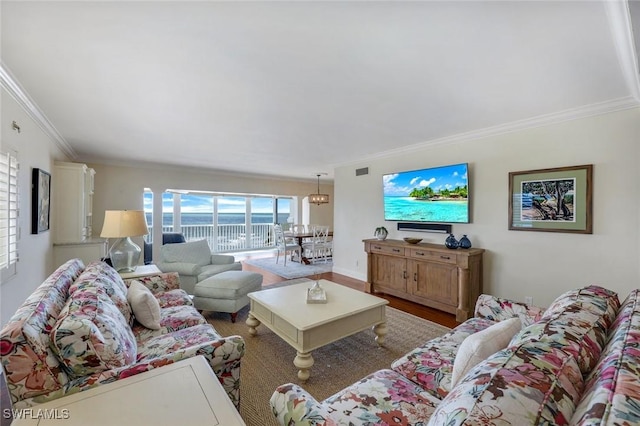 living area with visible vents, crown molding, and wood finished floors