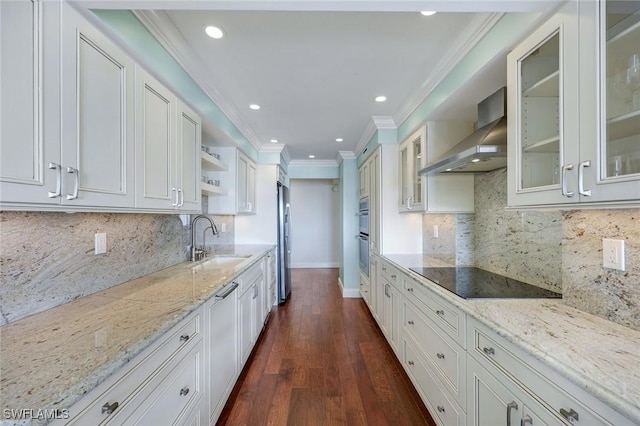 kitchen with black electric cooktop, a sink, wall chimney range hood, open shelves, and crown molding