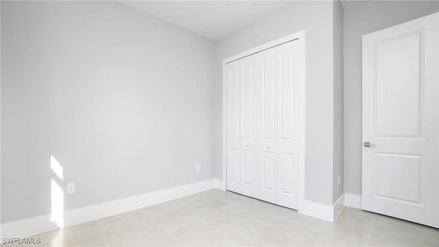 unfurnished bedroom with a closet, baseboards, and light tile patterned flooring