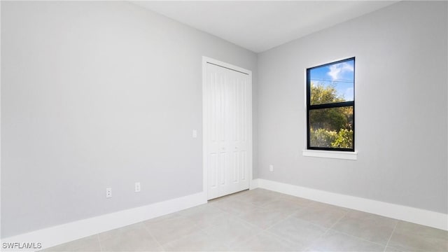 spare room featuring light tile patterned flooring and baseboards