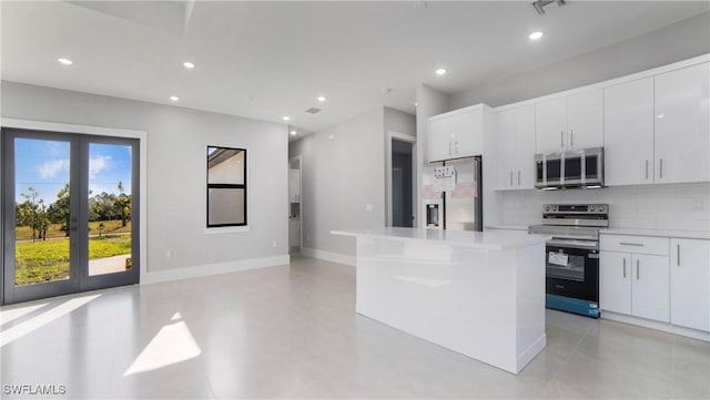 kitchen featuring decorative backsplash, a kitchen island, appliances with stainless steel finishes, and light countertops