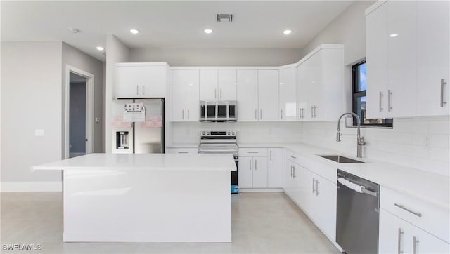 kitchen with tasteful backsplash, white cabinetry, stainless steel appliances, and a sink