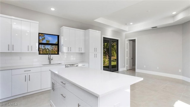 kitchen with baseboards, recessed lighting, a sink, light countertops, and tasteful backsplash