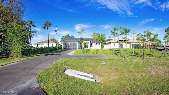 single story home featuring a front lawn, a garage, and driveway