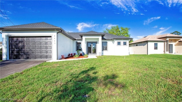 prairie-style home featuring stucco siding, an attached garage, driveway, and a front yard