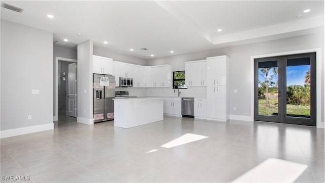 kitchen featuring visible vents, a kitchen island, decorative backsplash, appliances with stainless steel finishes, and a sink