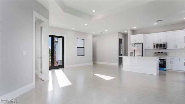 kitchen featuring decorative backsplash, white cabinets, a center island, and stainless steel appliances