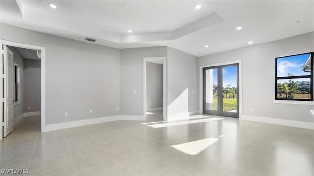 unfurnished room with visible vents, baseboards, a tray ceiling, recessed lighting, and light tile patterned flooring