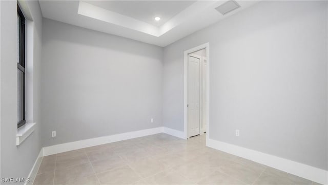 spare room with recessed lighting, baseboards, and a raised ceiling