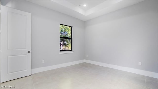 spare room with recessed lighting, a tray ceiling, baseboards, and light tile patterned flooring