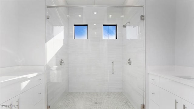 bathroom featuring a stall shower and two vanities