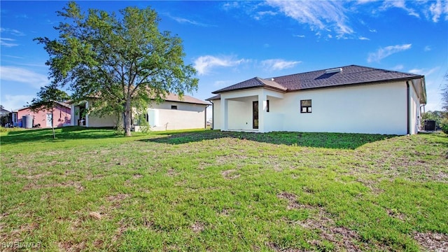 back of property with stucco siding, a lawn, and cooling unit