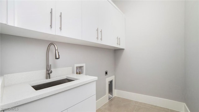 washroom with baseboards, light tile patterned floors, cabinet space, hookup for an electric dryer, and a sink