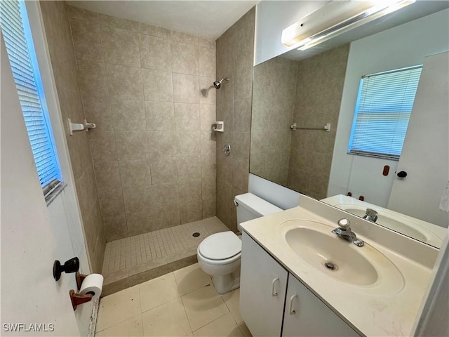 full bathroom with a tile shower, vanity, toilet, and tile patterned floors