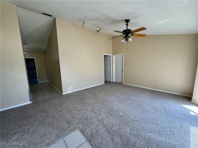 carpeted spare room featuring baseboards, a ceiling fan, vaulted ceiling, and track lighting