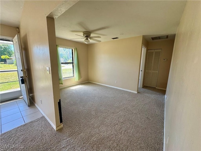 carpeted spare room with visible vents, ceiling fan, and baseboards