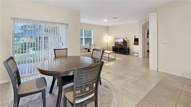 dining area with light tile patterned floors, baseboards, and arched walkways