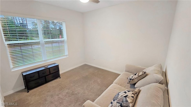 living area featuring carpet floors, baseboards, and a ceiling fan