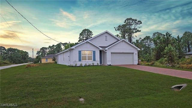 ranch-style home with a yard, decorative driveway, and an attached garage