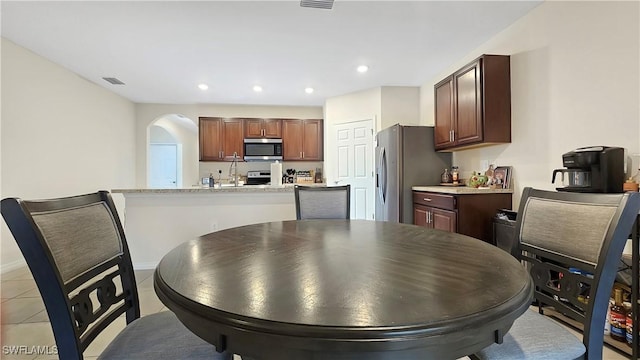 kitchen with arched walkways, light tile patterned floors, recessed lighting, visible vents, and appliances with stainless steel finishes