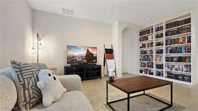 sitting room featuring arched walkways, light tile patterned floors, visible vents, and built in features