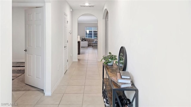 hall featuring baseboards, visible vents, arched walkways, and light tile patterned flooring