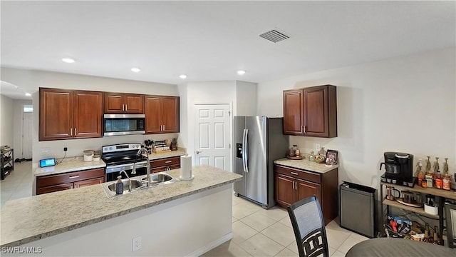 kitchen featuring an island with sink, visible vents, stainless steel appliances, and a sink