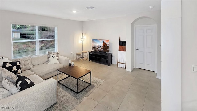 living area with light tile patterned floors, visible vents, arched walkways, and recessed lighting