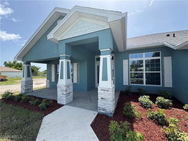 106 SE 5th Ave, Cape Coral, FL 33990 - doorway to property featuring stucco siding, covered porch, and a shingled roof