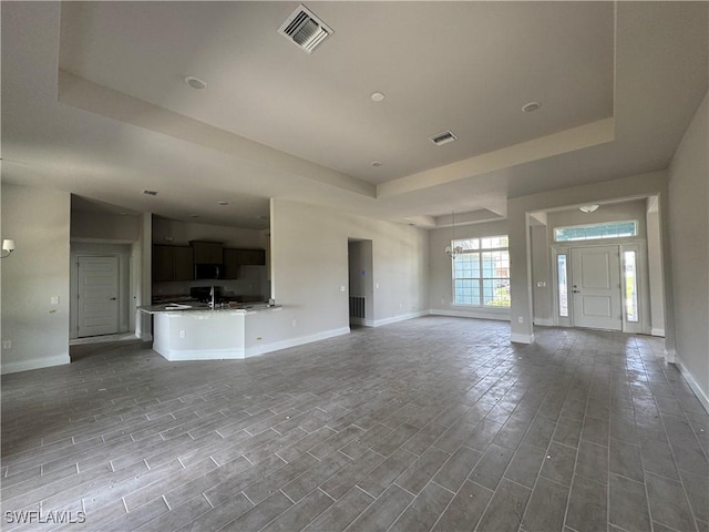 106 SE 5th Ave, Cape Coral, FL 33990 - unfurnished living room with a raised ceiling, baseboards, and wood finished floors
