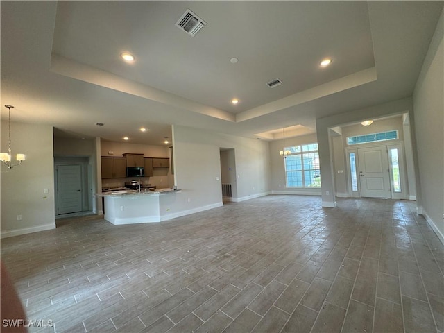 106 SE 5th Ave, Cape Coral, FL 33990 - unfurnished living room with a chandelier, a raised ceiling, baseboards, light wood-style flooring, and recessed lighting