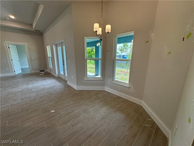 106 SE 5th Ave, Cape Coral, FL 33990 - spare room featuring baseboards, a chandelier, wood finished floors, and a raised ceiling