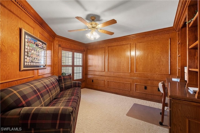 carpeted home office featuring wood walls, crown molding, and a ceiling fan