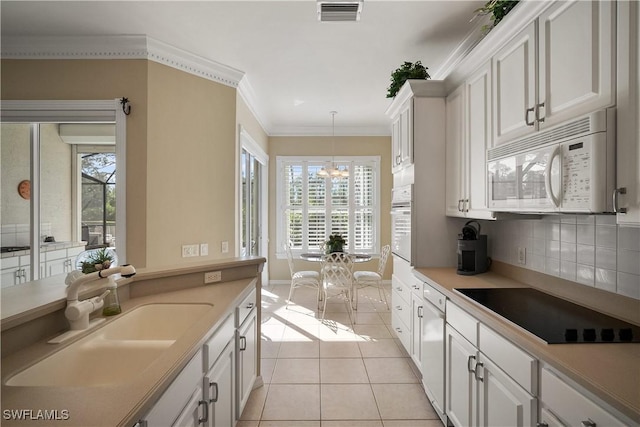 kitchen featuring light tile patterned floors, white appliances, a sink, visible vents, and crown molding