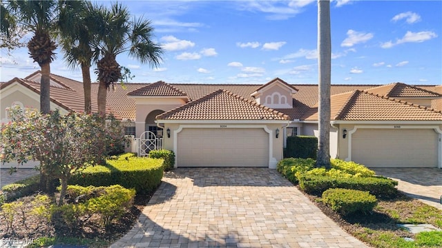 mediterranean / spanish home with a garage, a tile roof, decorative driveway, and stucco siding