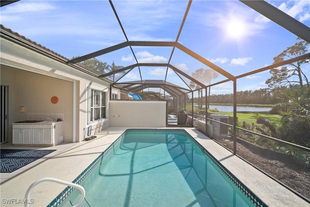 outdoor pool with a water view, a patio area, and a lanai